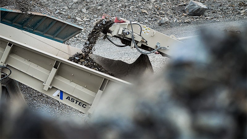 aggregate material moving from one piece of equipment to another at a quarry